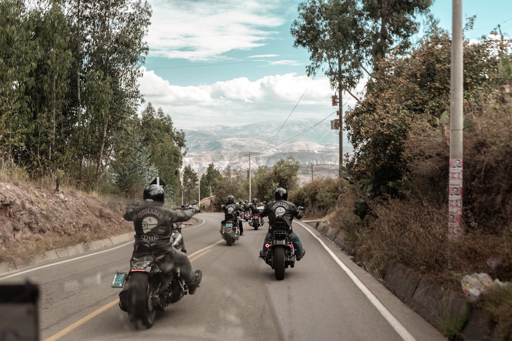 a group of people riding motorcycles down a road