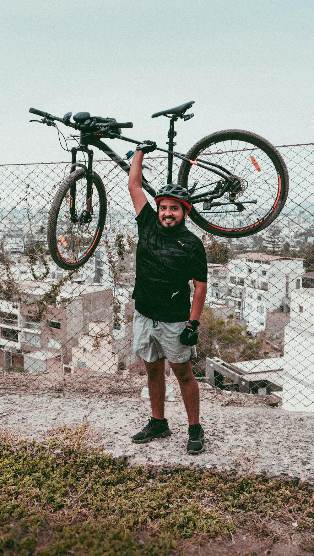 a man holding up a bike on top of a hill
