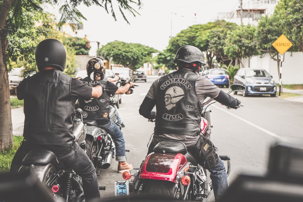 a group of men riding motorcycles down a street