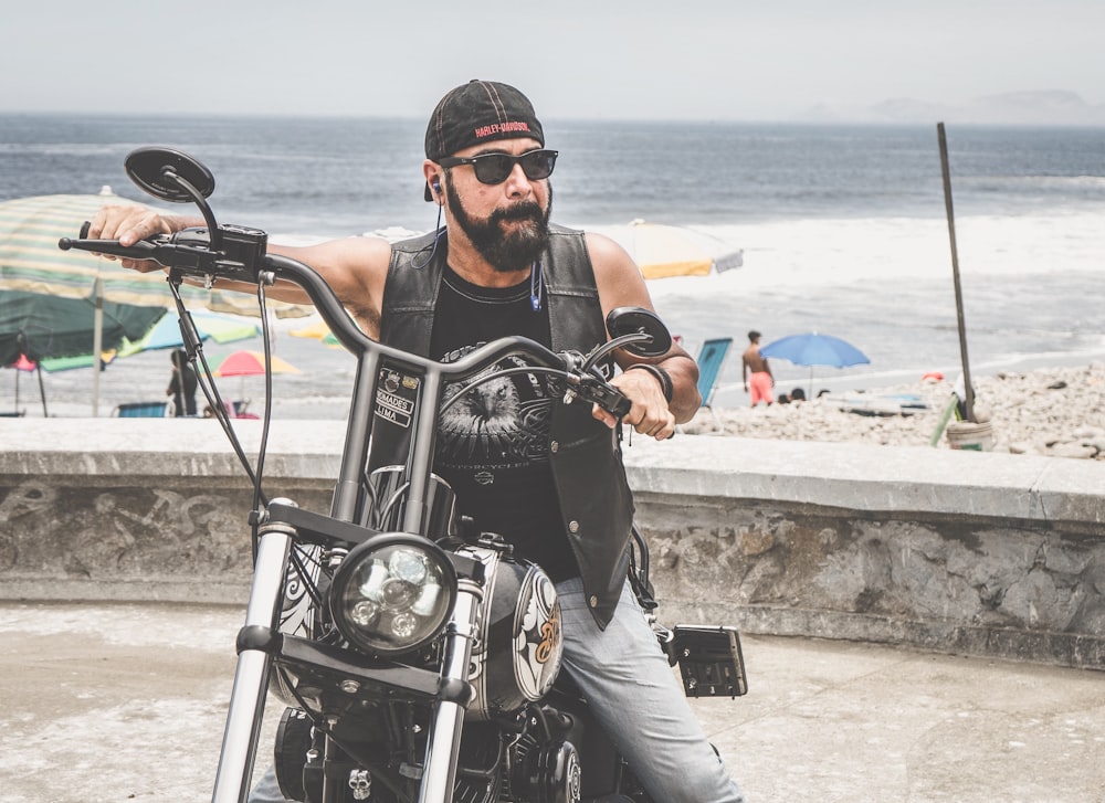 a man sitting on a motorcycle next to the ocean