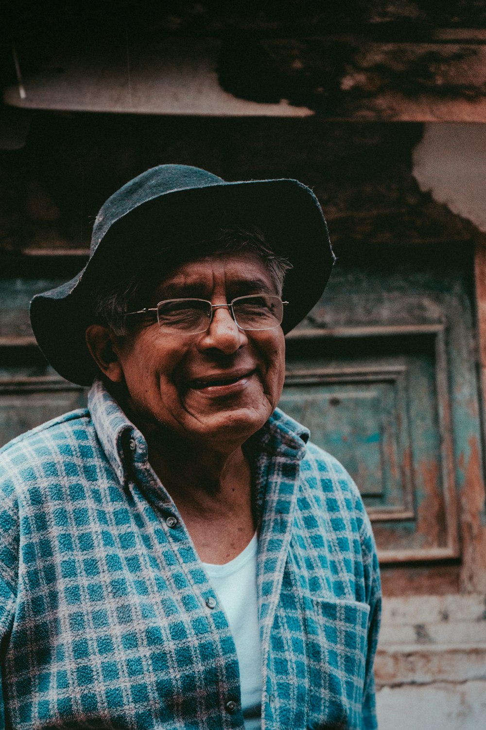 a man wearing a hat and glasses standing in front of a building