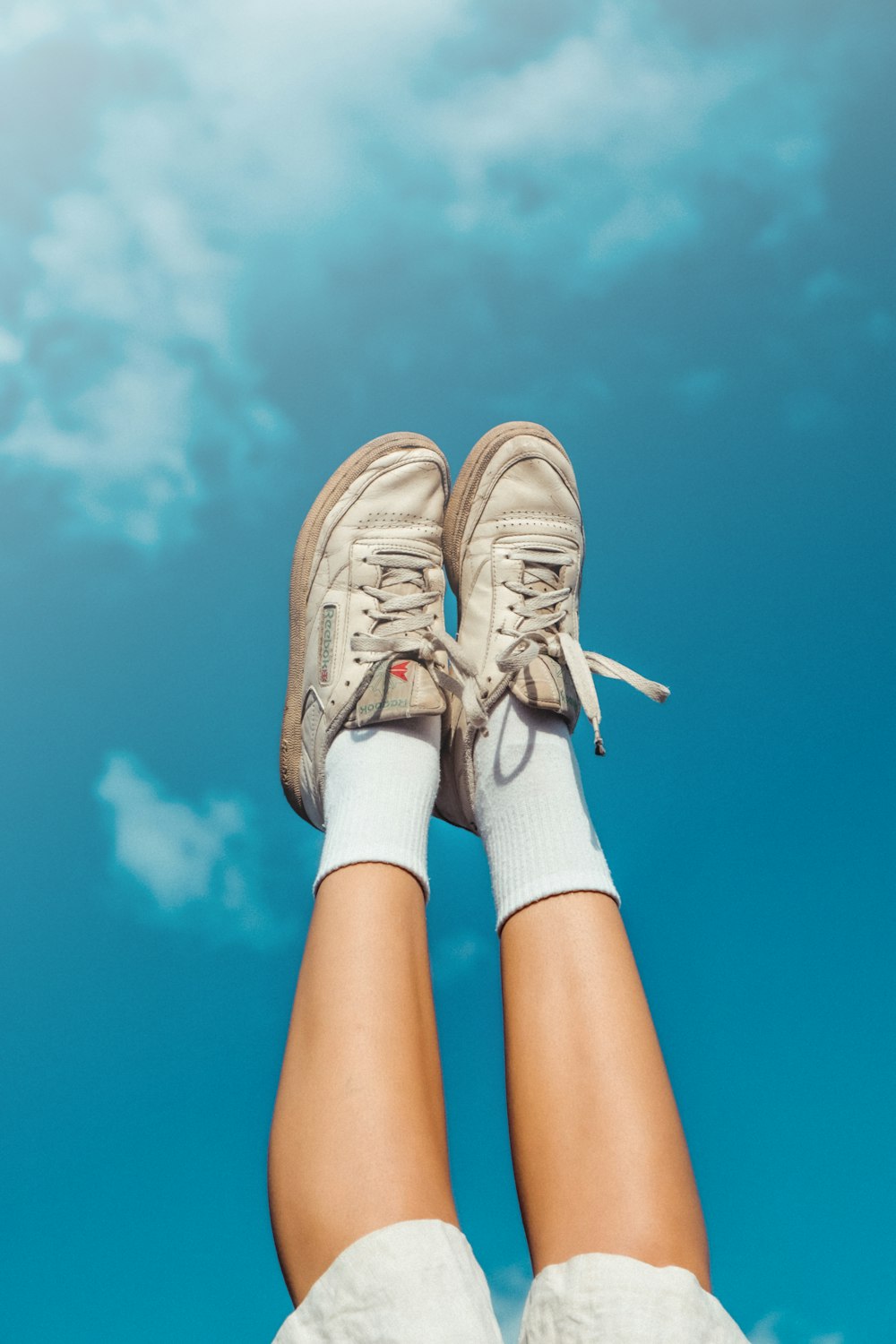 a person's legs with white socks and sneakers