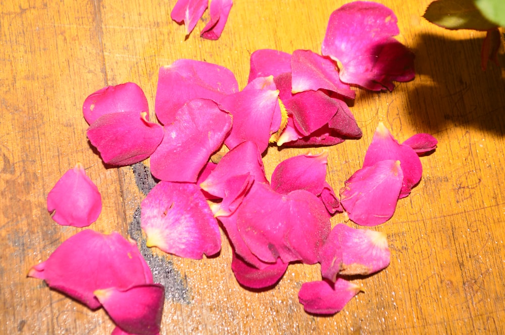 a wooden table topped with lots of pink petals