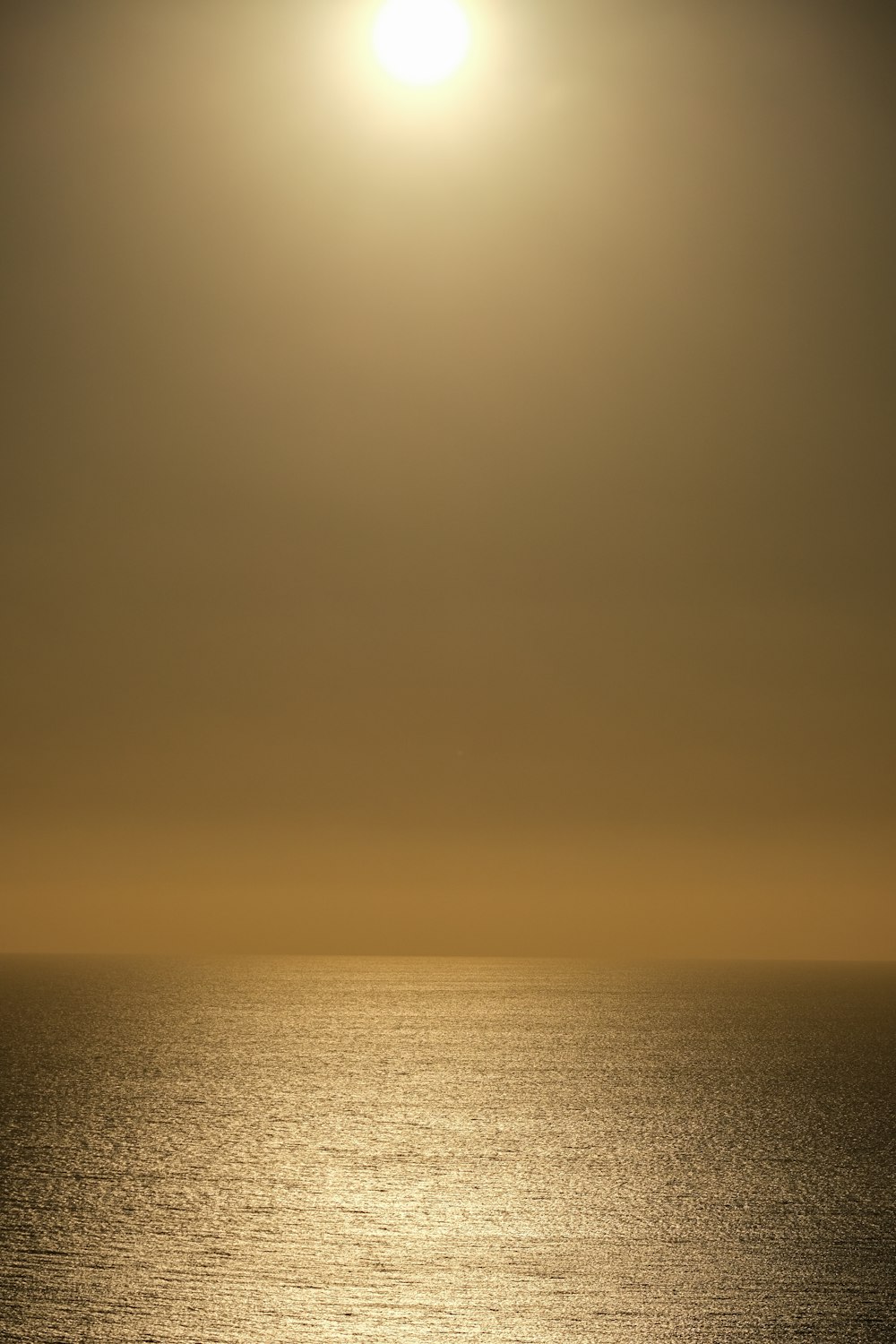 the sun is shining over the ocean on a hazy day