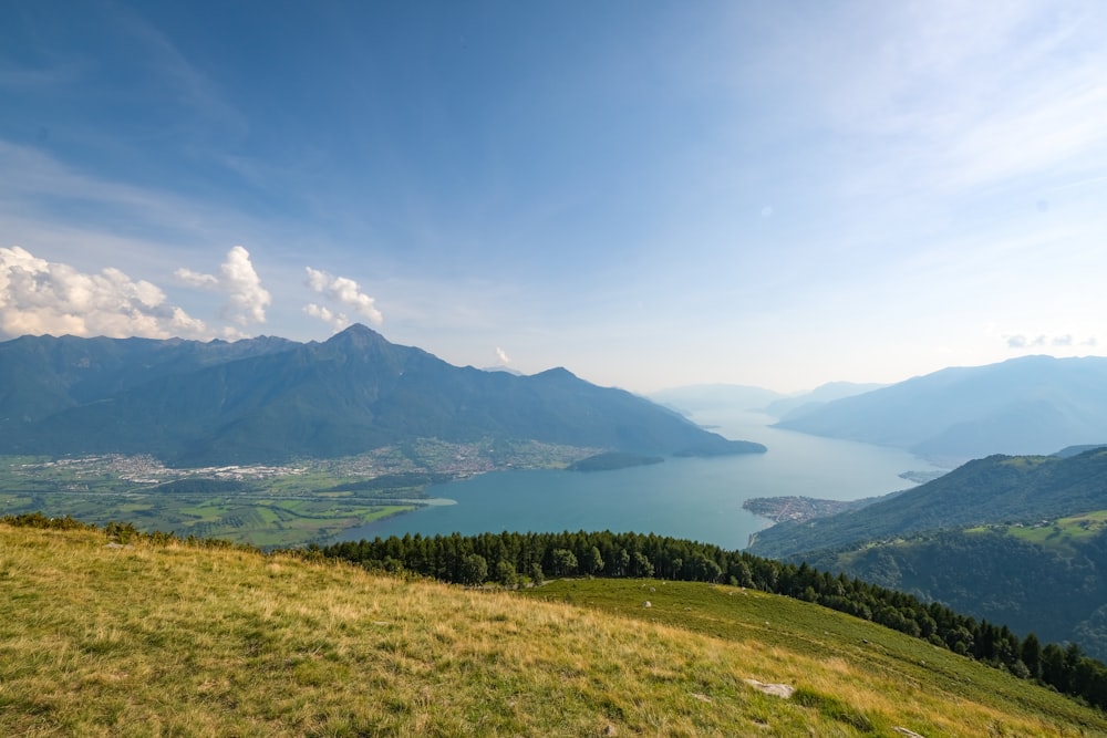 a grassy hill with a lake and mountains in the background