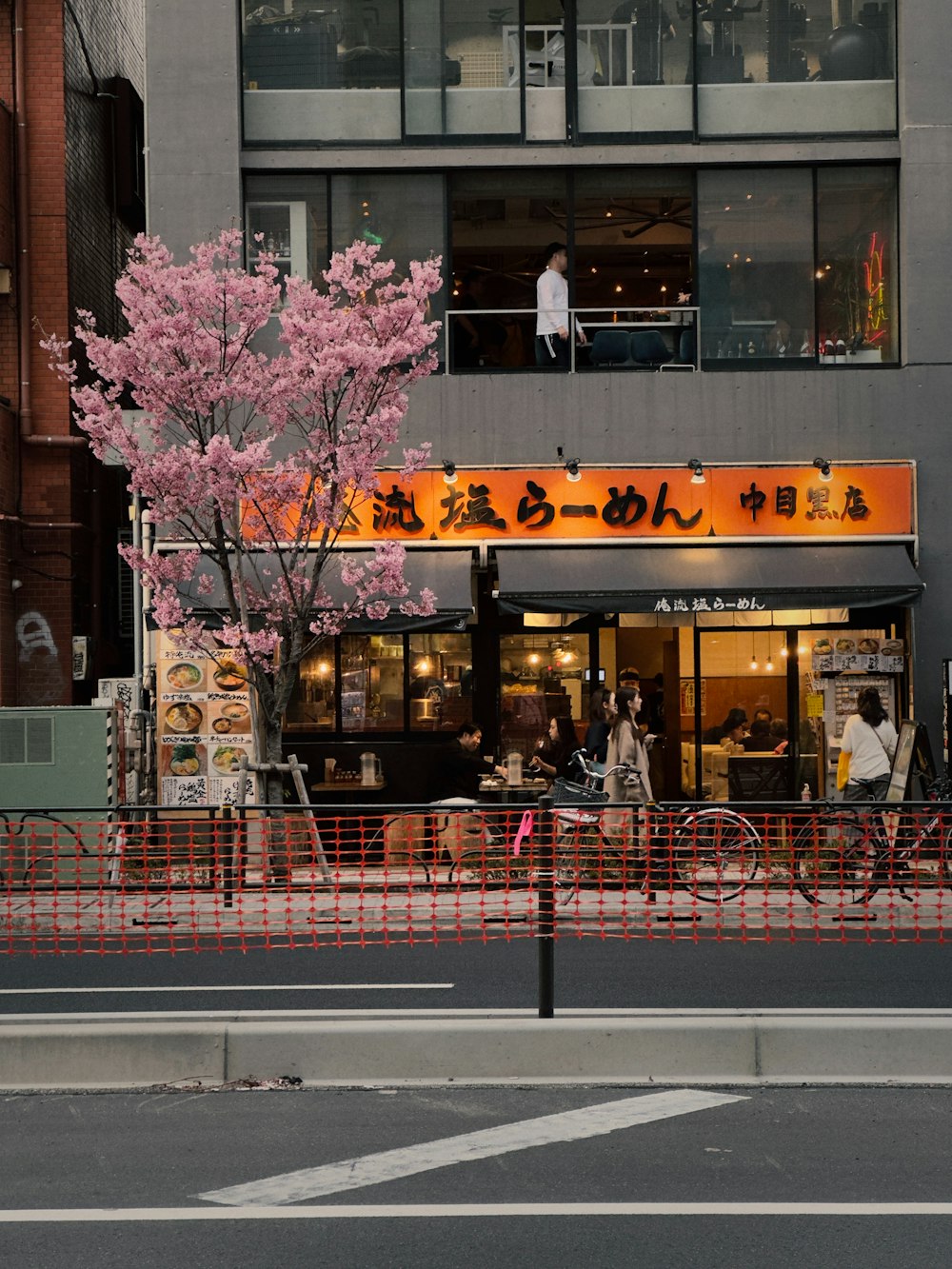 a city street with a red fence and a tall building