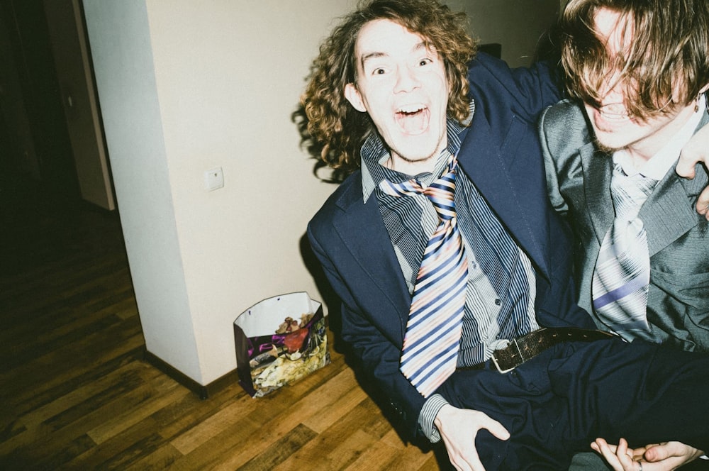 two men in suits and ties sitting on the floor