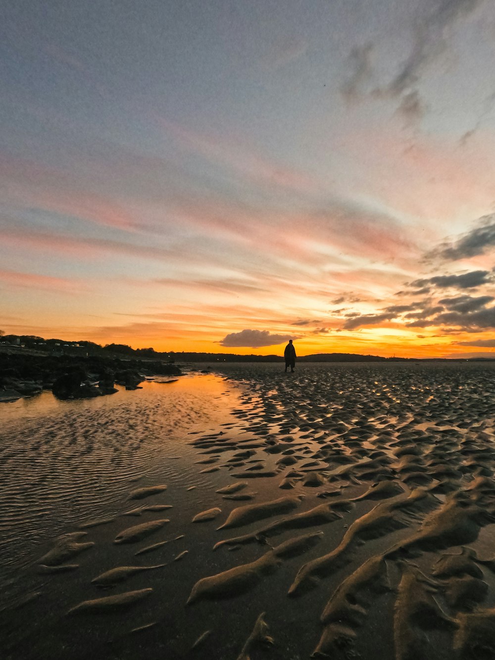 a person walking on a beach at sunset