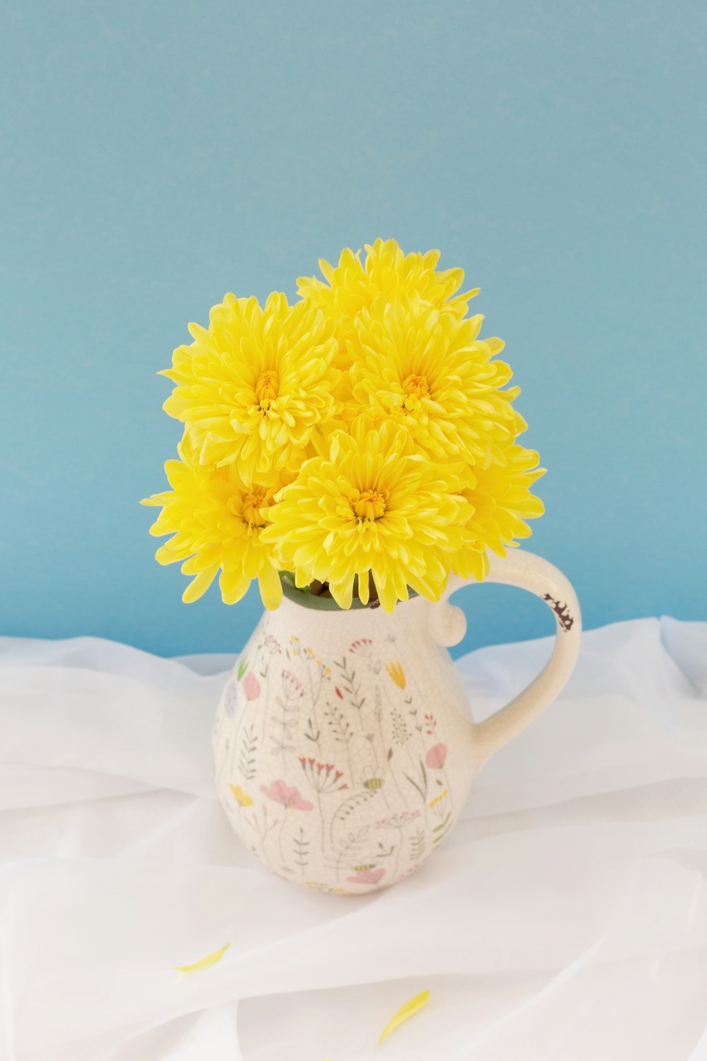 a white pitcher with yellow flowers in it