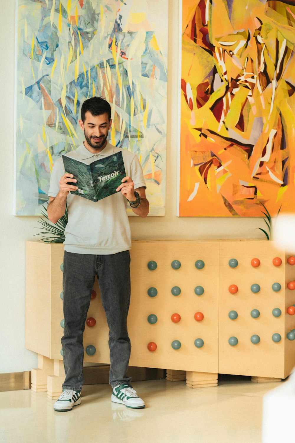 a man standing in front of a painting holding a book