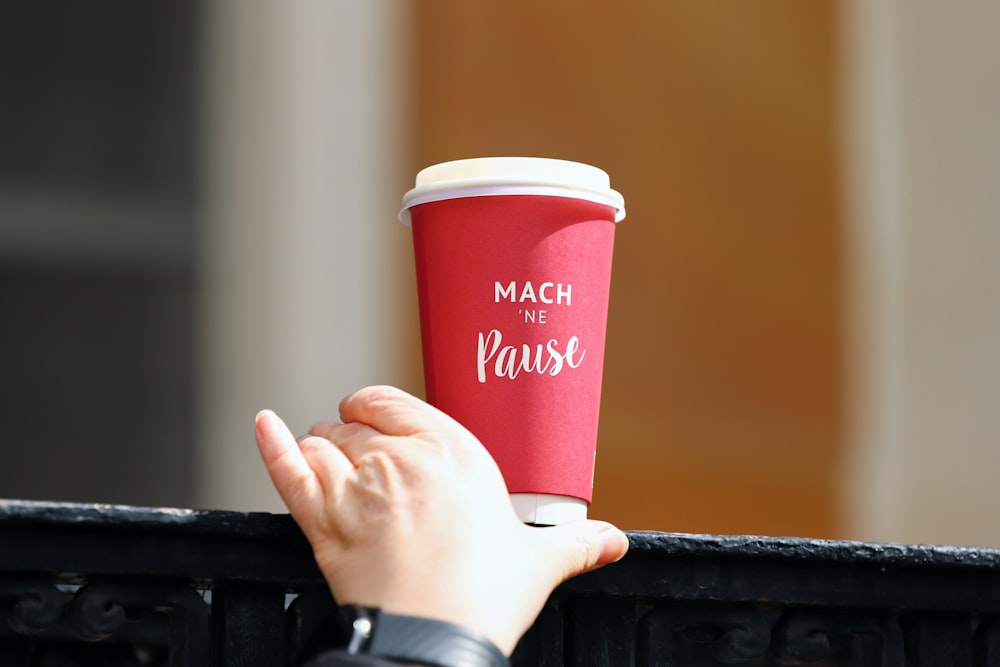 a person holding a red cup of coffee