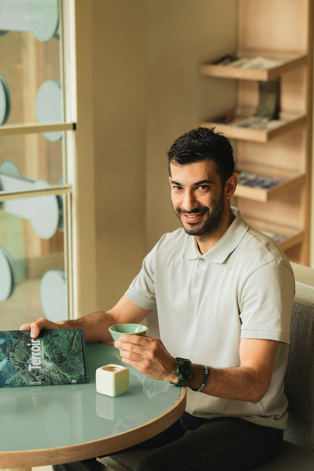 a man sitting at a table with a cup of coffee