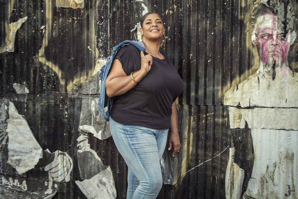 a woman standing in front of a wall covered in graffiti