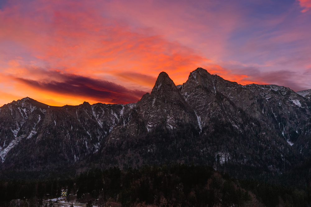 Una vista del atardecer de una cadena montañosa con un cielo rojo