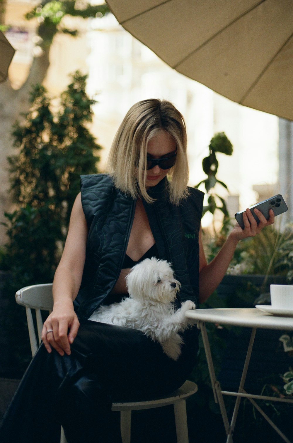 uma mulher sentada em uma mesa com um cão branco