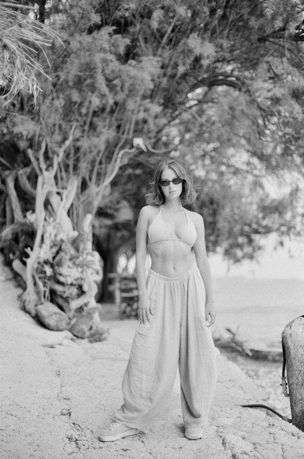 a black and white photo of a woman standing on a beach