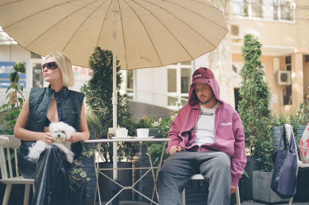 two people sitting at a table with an umbrella