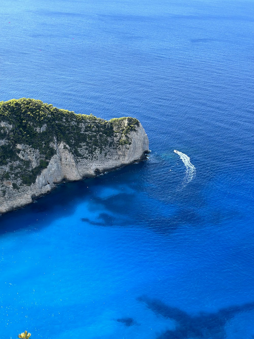 a boat is in the blue water near a cliff