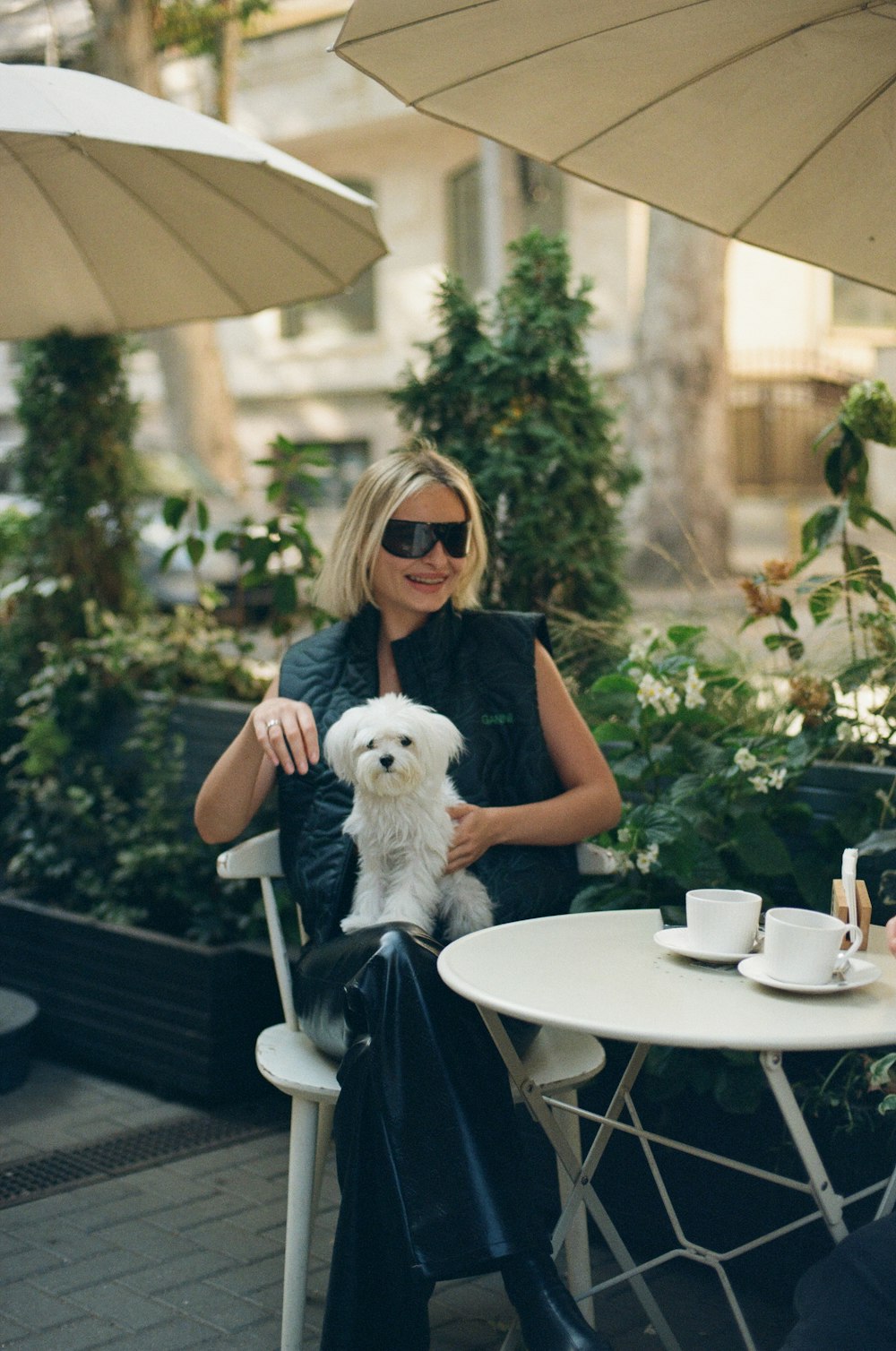 a woman sitting at a table with a white dog