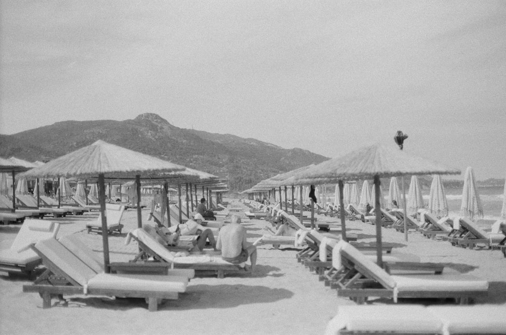 a black and white photo of beach chairs and umbrellas