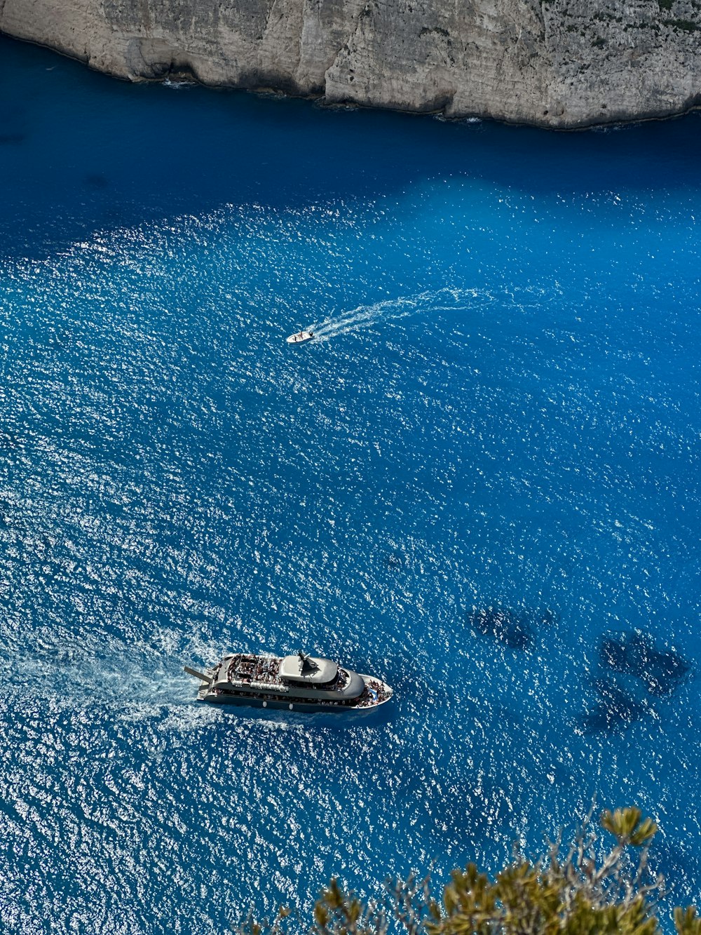 a boat floating on a body of water next to a cliff