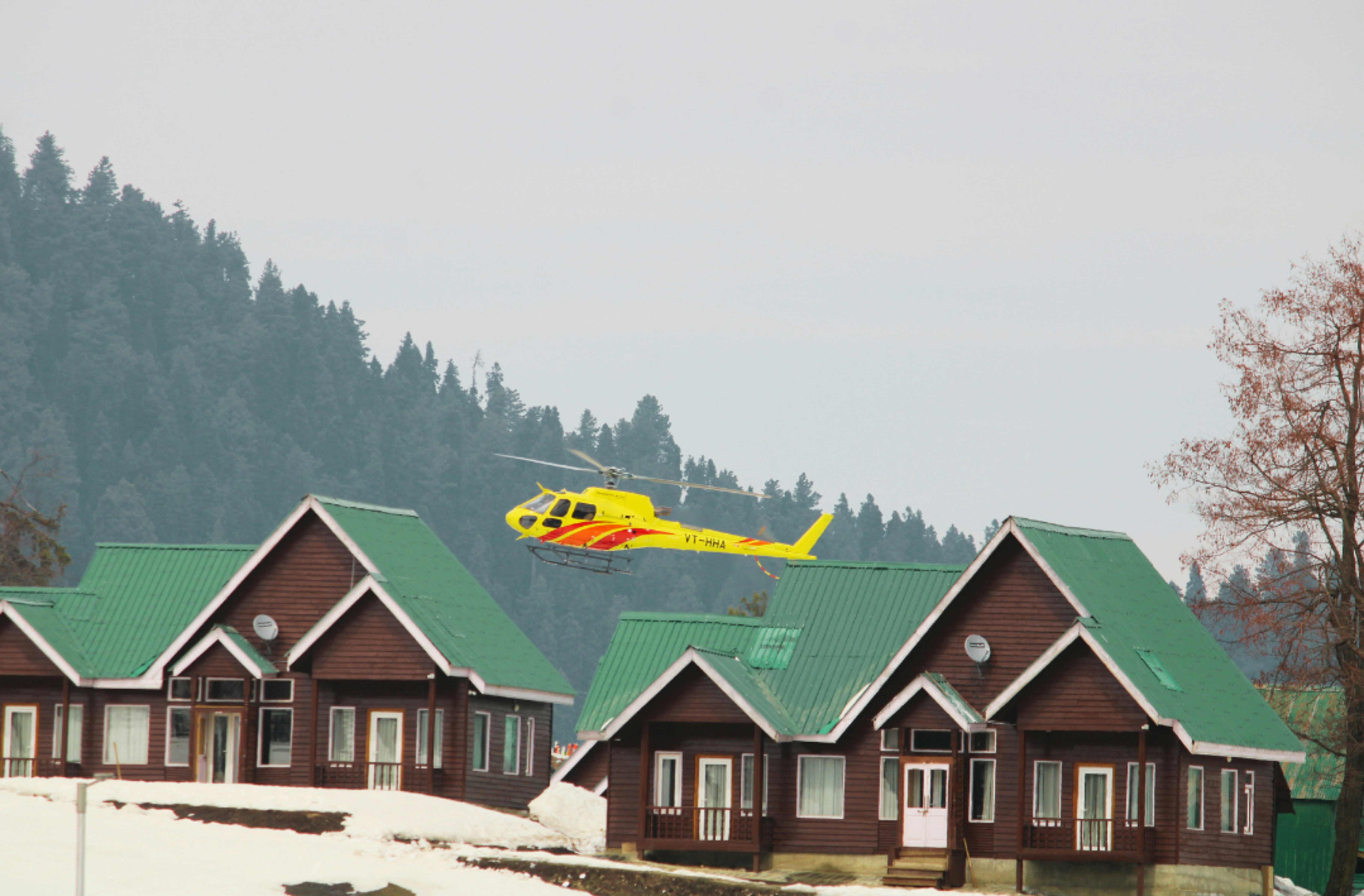 a helicopter flying over a row of houses, Gulmarg