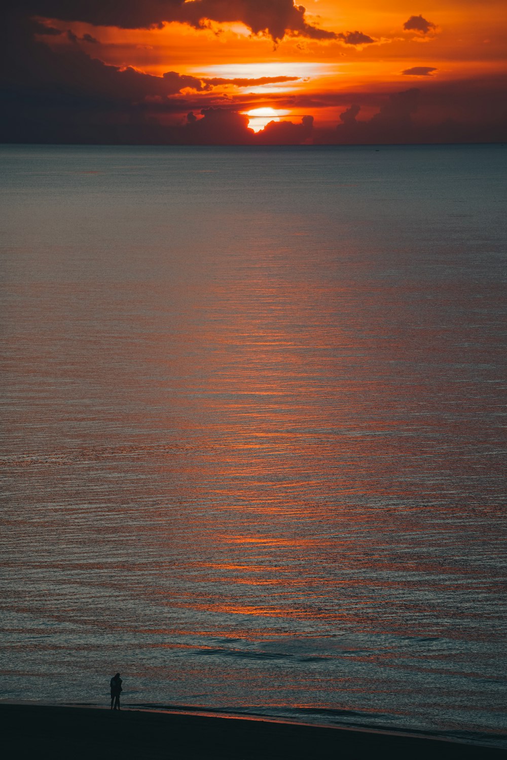 a person standing on a beach at sunset