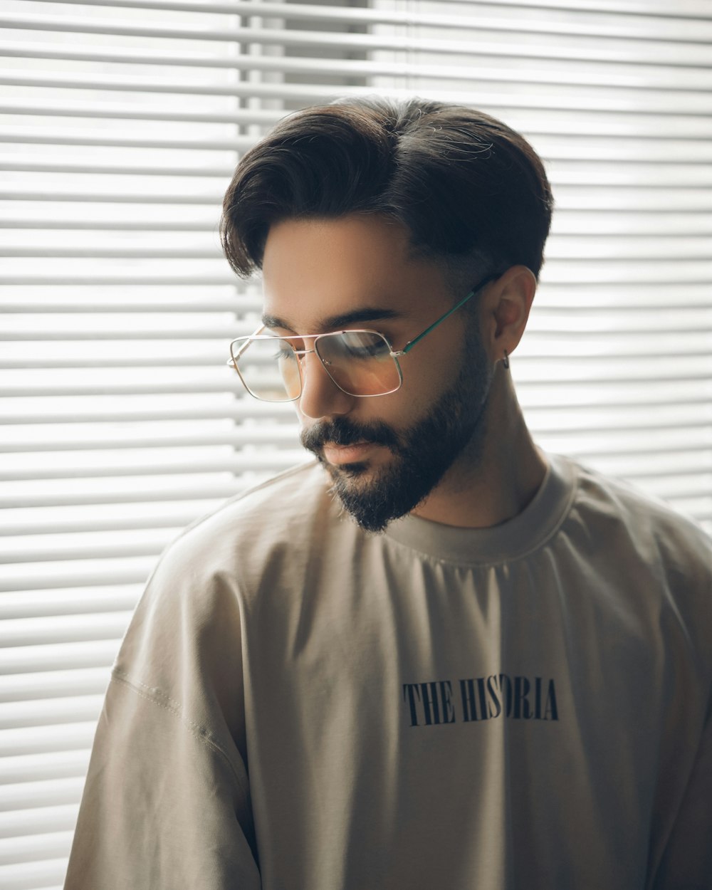 a man with a beard and glasses standing in front of a window