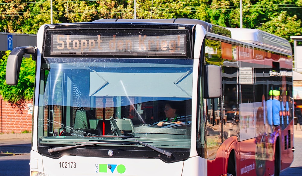 a white and red bus driving down a street