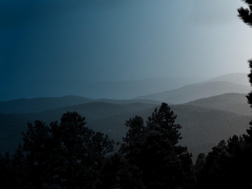 a view of a mountain range with trees in the foreground