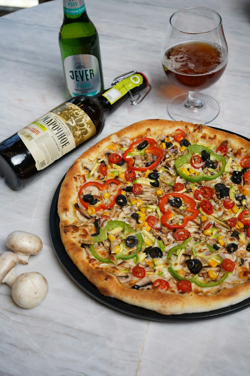 a pizza sitting on top of a table next to a bottle of beer