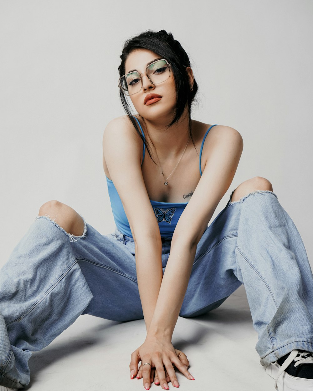 a woman with glasses sitting on the ground