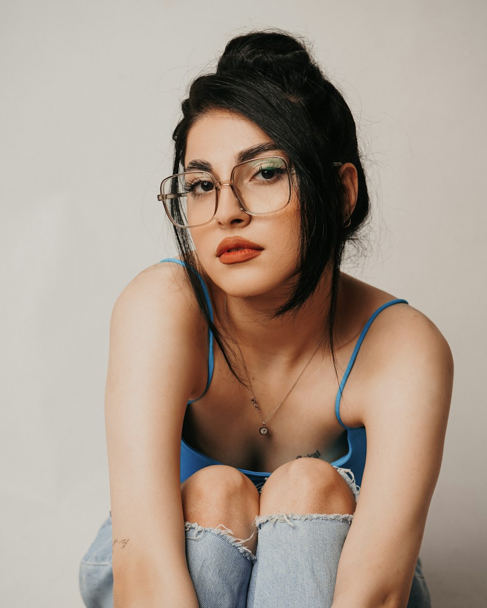 a woman with glasses sitting on the floor