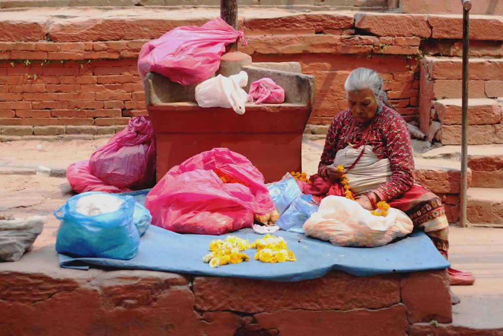 a woman sitting on a blue blanket next to a pile of bags