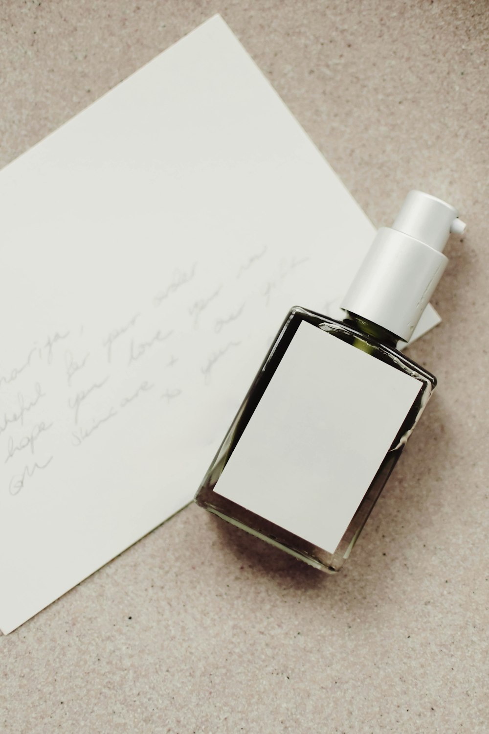 a bottle of perfume sitting next to a piece of paper