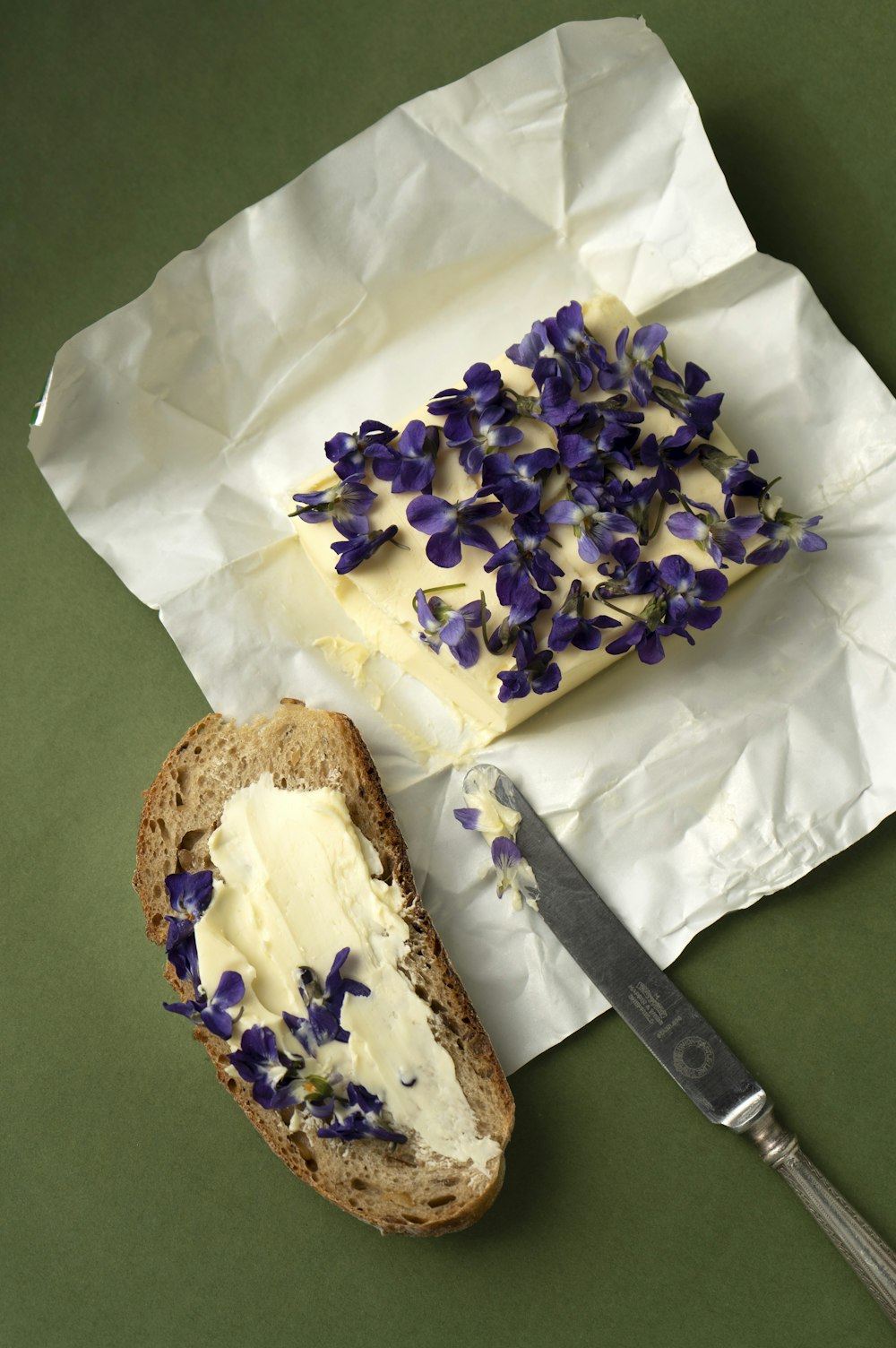 a piece of bread with butter and purple flowers on it