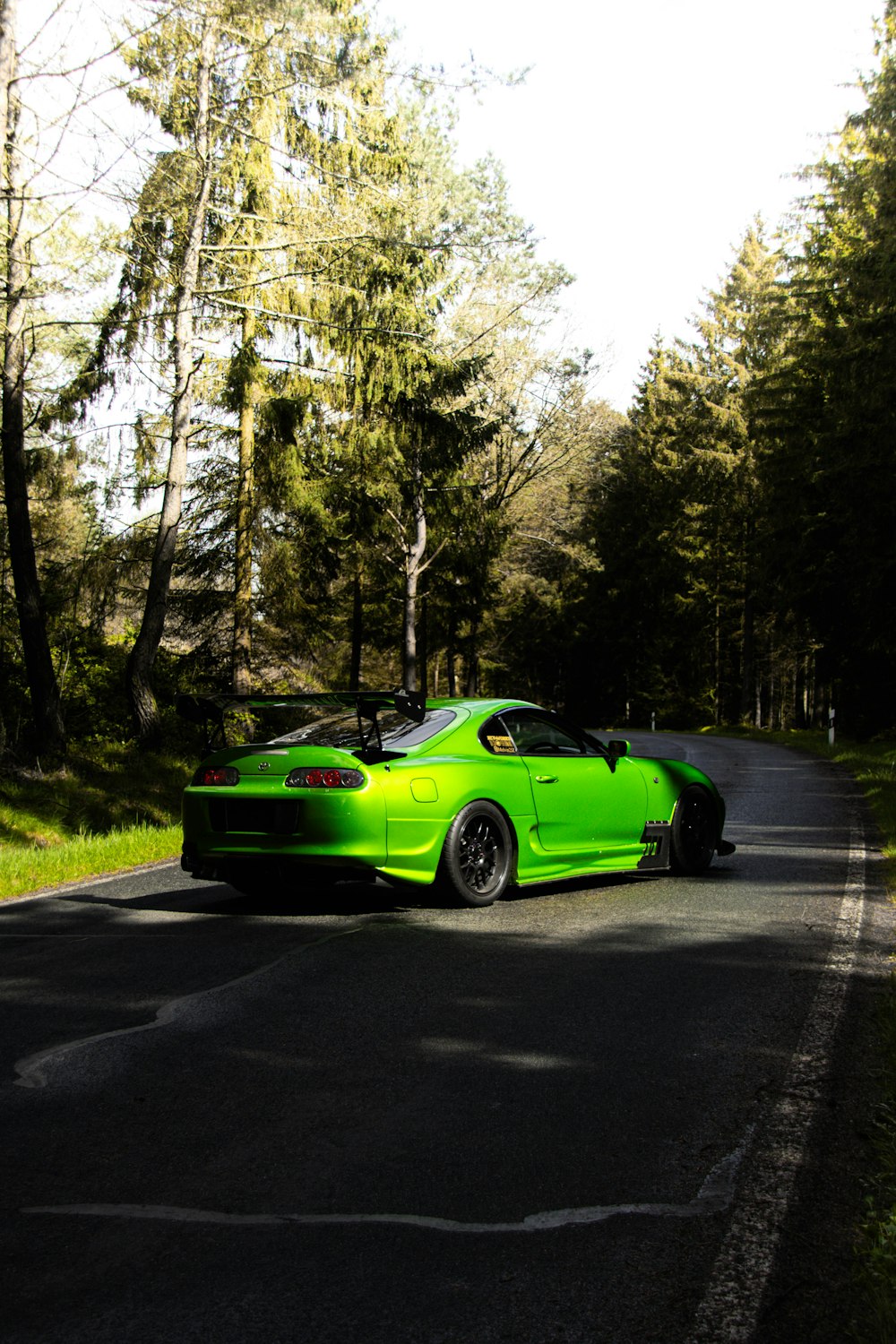 a green sports car driving down the road