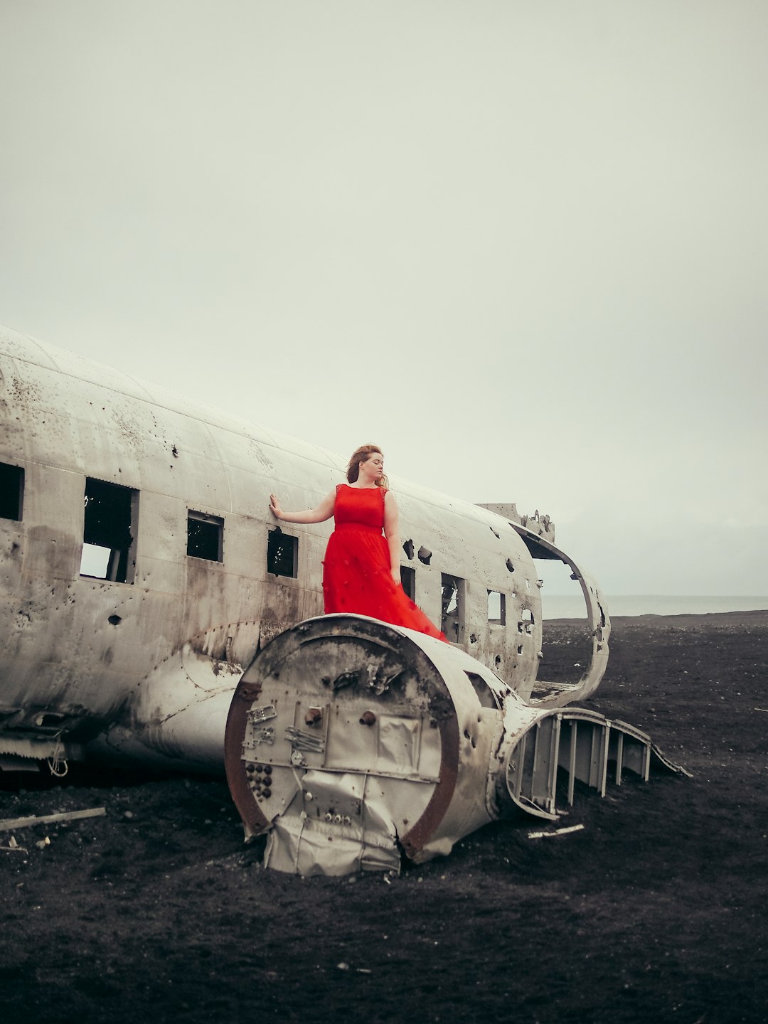 A model wearing red on the iconic crashed plane in Iceland, shot on a vintage slr and edited to look like film.