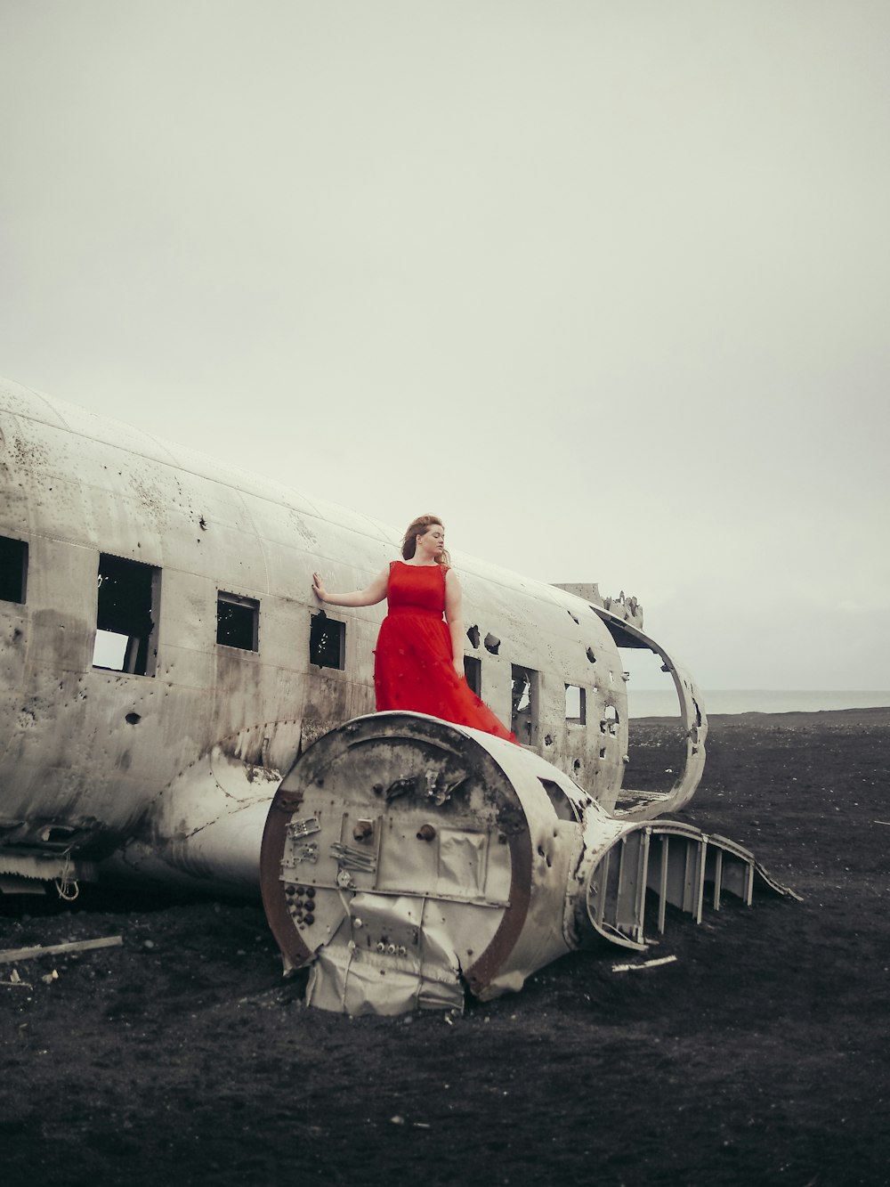 a woman in a red dress standing next to an airplane