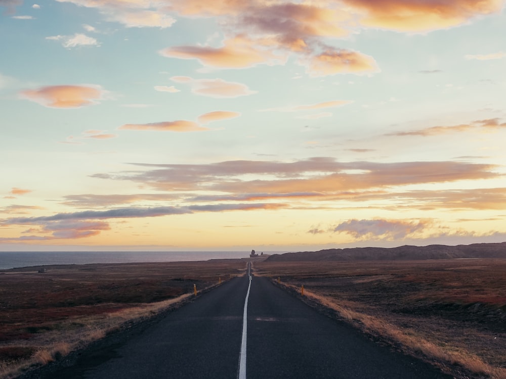 a long road with a sky filled with clouds