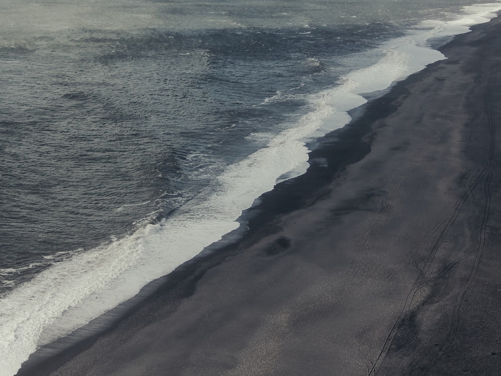 a black sand beach with waves coming in to shore