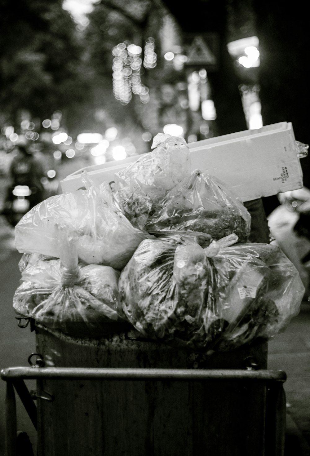 Una foto in bianco e nero di un bidone della spazzatura pieno di sacchetti