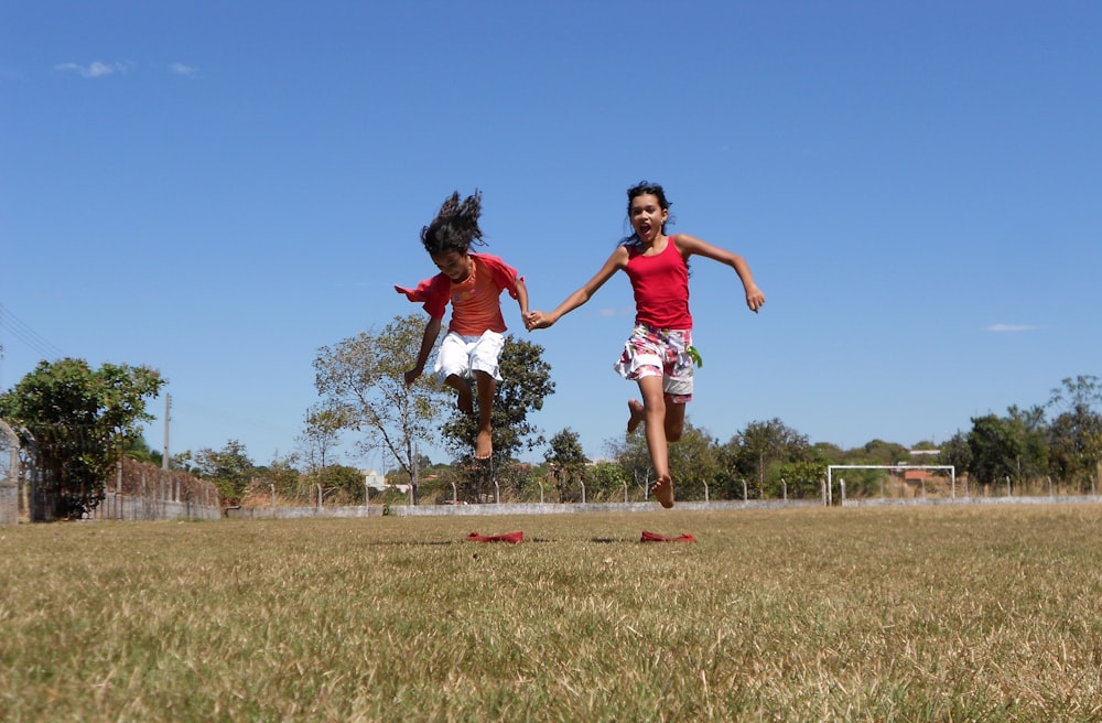 a couple of people that are running in the grass