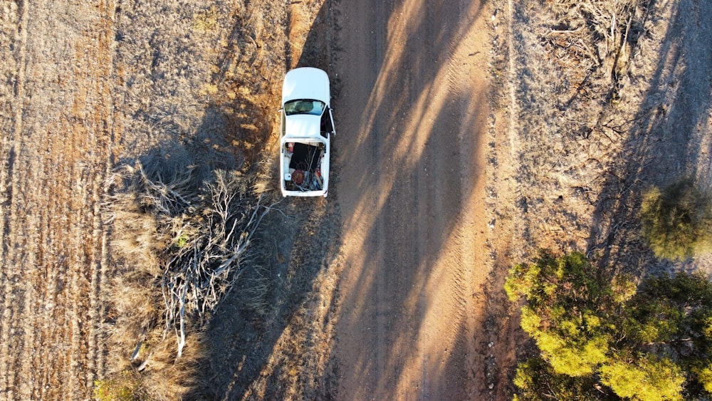 an aerial view of a car driving down a dirt road