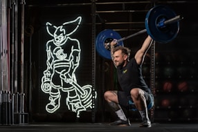 a man squatting with a barbell in his hands