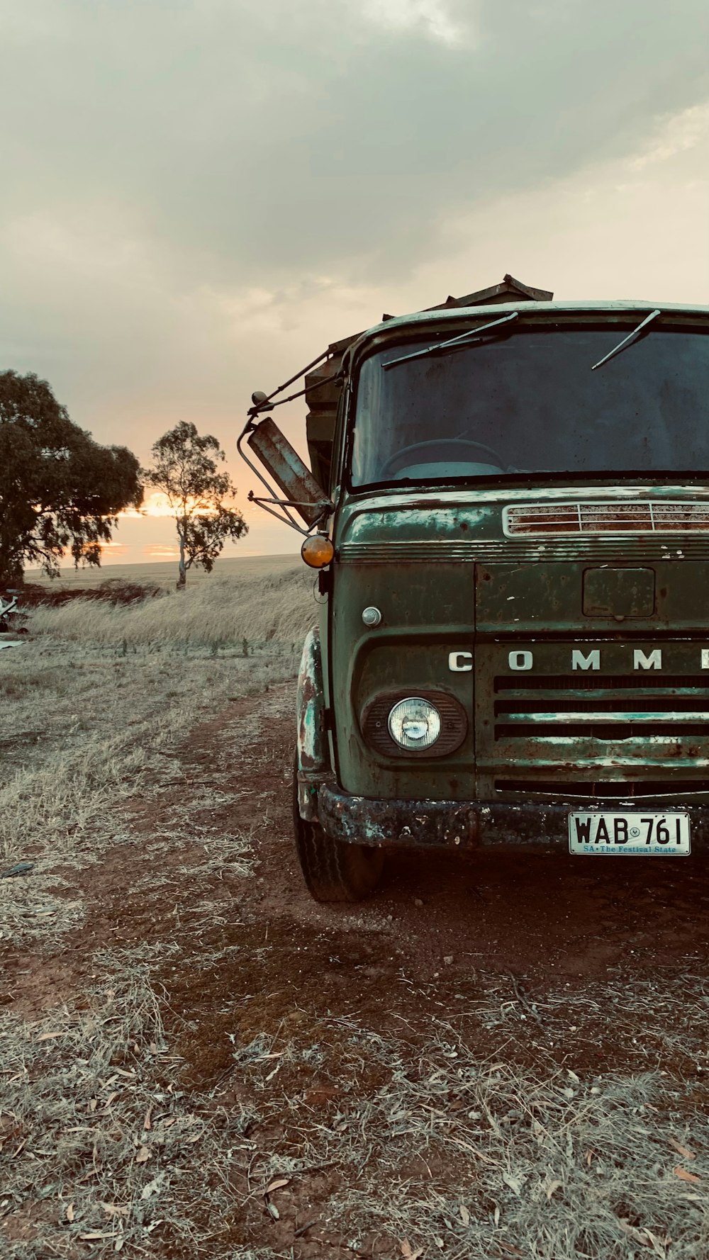 a green truck parked on a dirt road