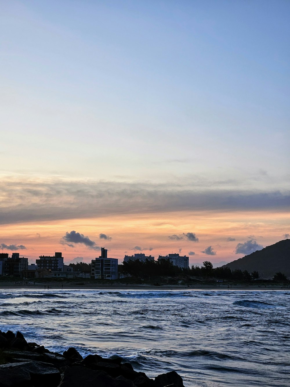 a view of a city and the ocean at sunset