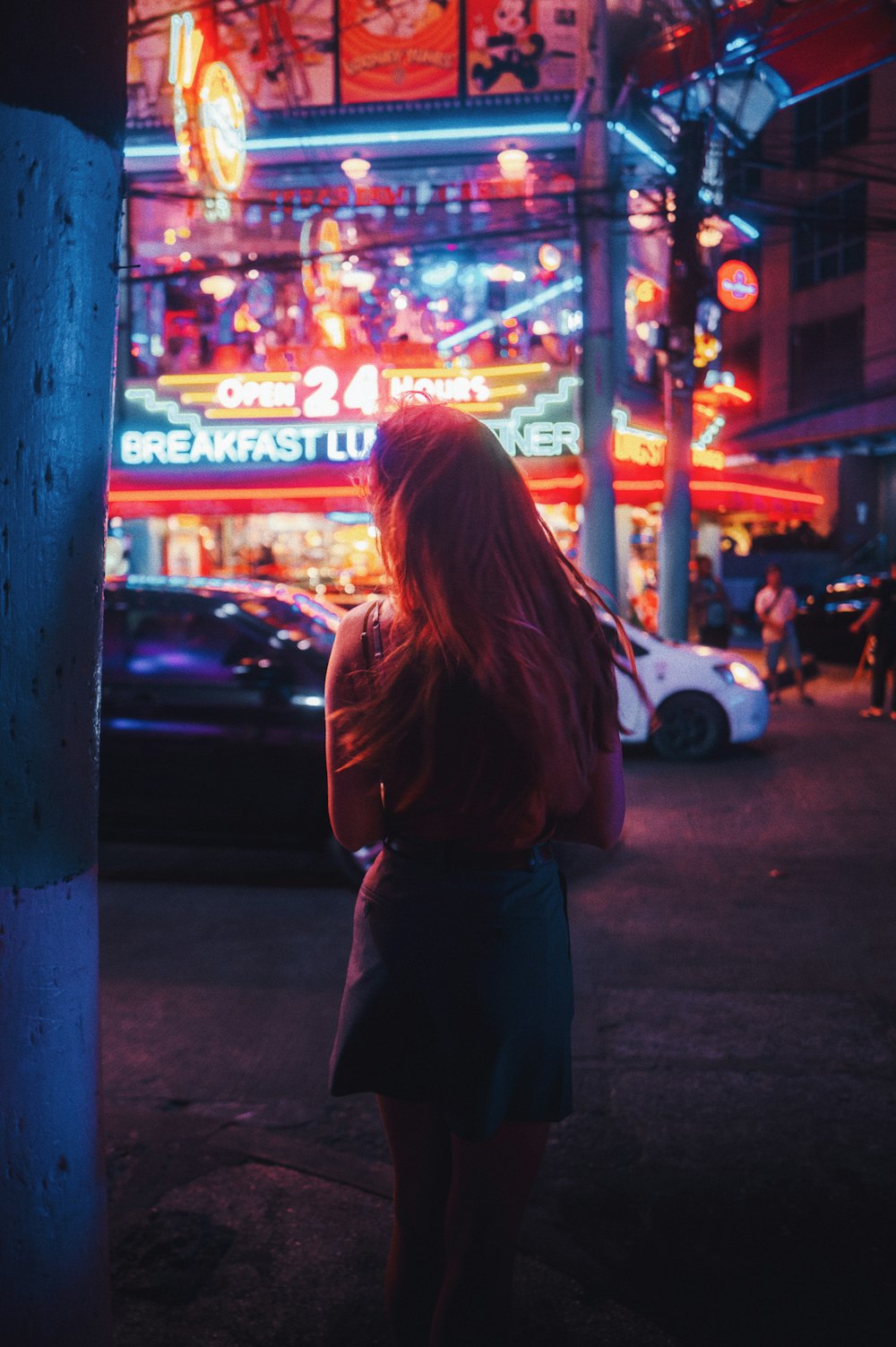 una mujer de pie frente a un edificio iluminado con luces de neón