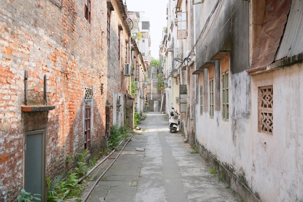 a narrow alley with a scooter parked on the side