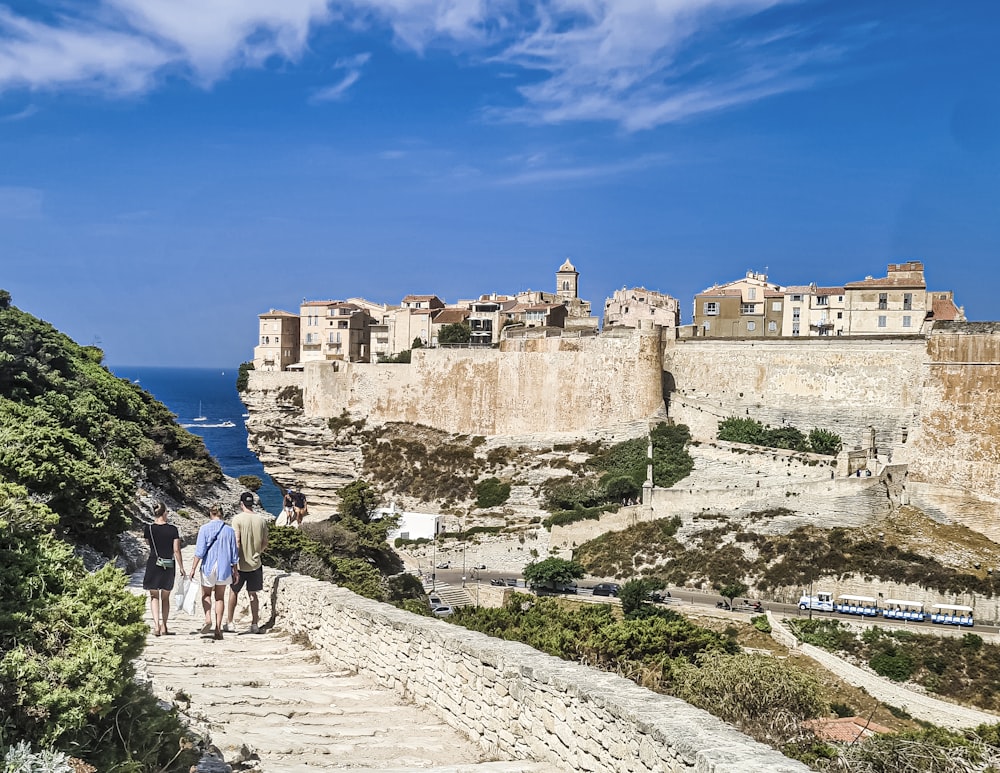 a group of people walking down a stone walkway next to the ocean